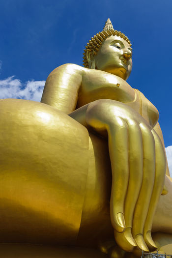 Low angle view of statue of buddha against blue sky