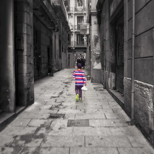 Rear view of boy walking on cobblestone