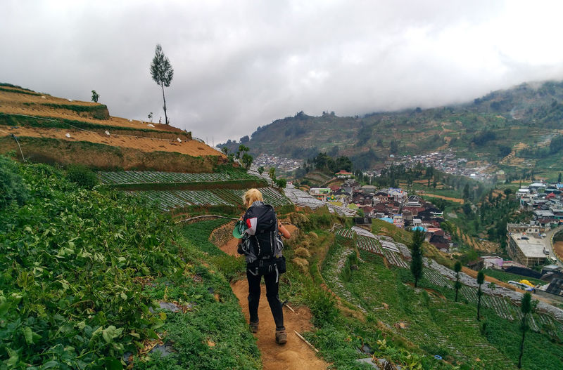 Rear view of woman wearing backpack walking on field