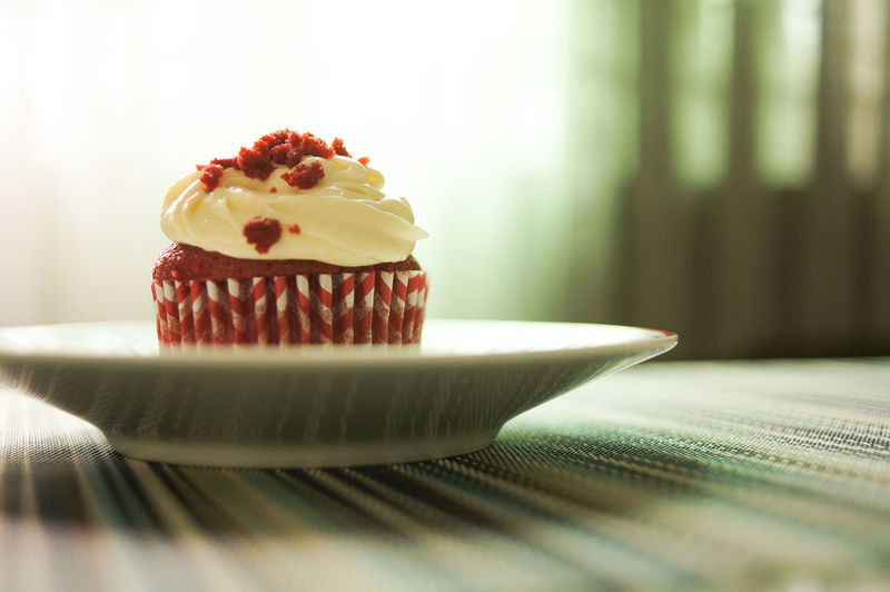 Close-up of red velvet cupcake with cream cheese frosting on table