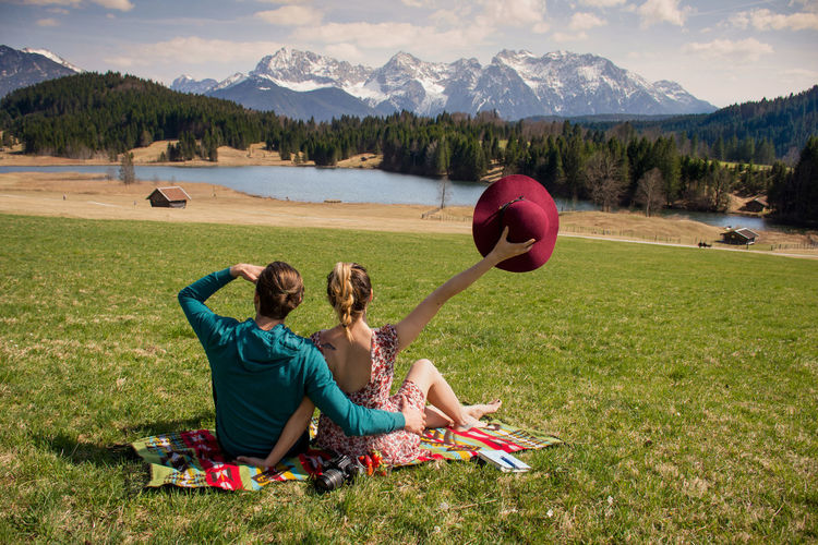 Friends sitting on field against mountain