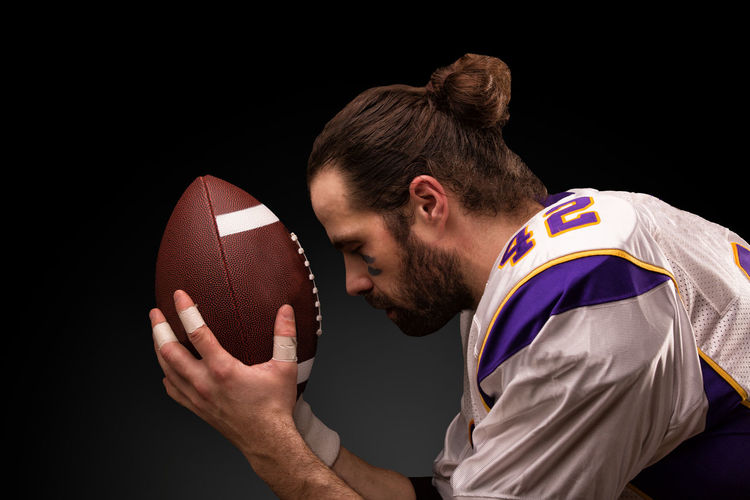 Side view of man playing with ball against black background