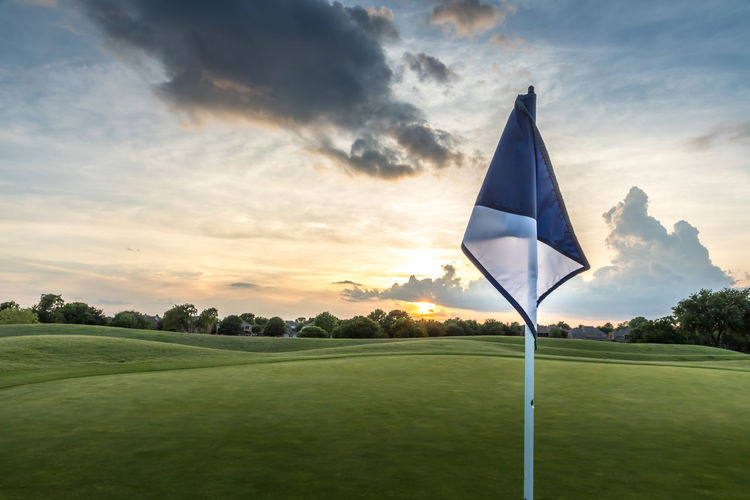 Flag on the green of a gold course  against sky during sunset