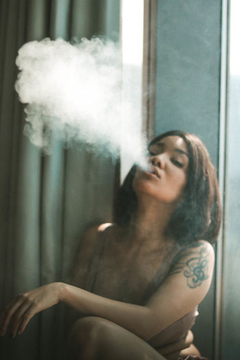 Portrait of sensuous woman smoking at home