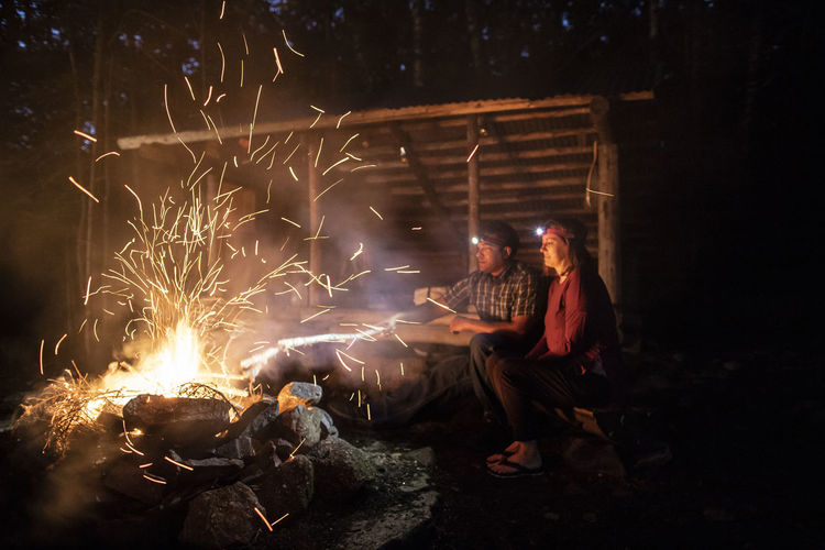 Sparks rise from a campfire as two hikers watch, appalachian trail.