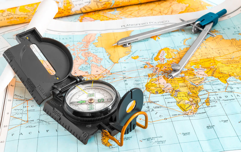 High angle view of navigational compass and drawing compass on world map