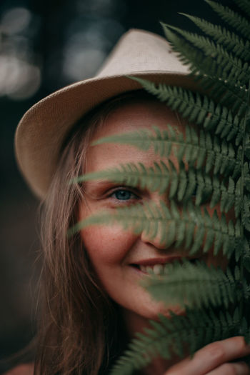 Young girl with freckles without makeup in the woods with a fern