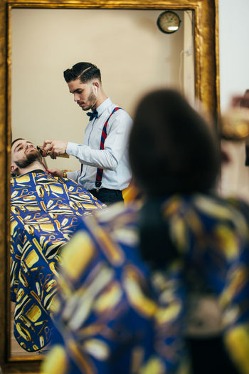 A barber cuts the beard of a man with a clipper in a barbershop