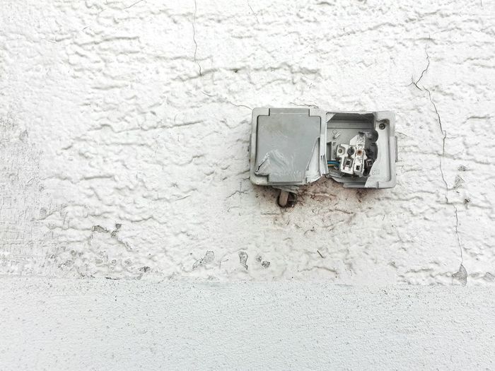 Close-up of abandoned fuse box on white wall