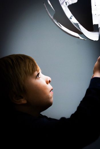 Boy looking at illuminated lighting equipment against gray background
