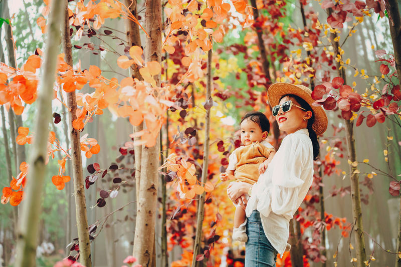 Low section of child standing by tree during autumn