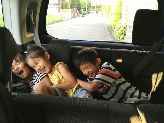 Cheerful siblings enjoying in car