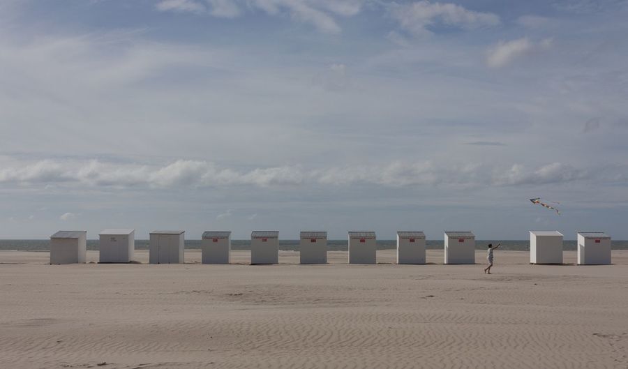 Hooded chairs on beach against sky