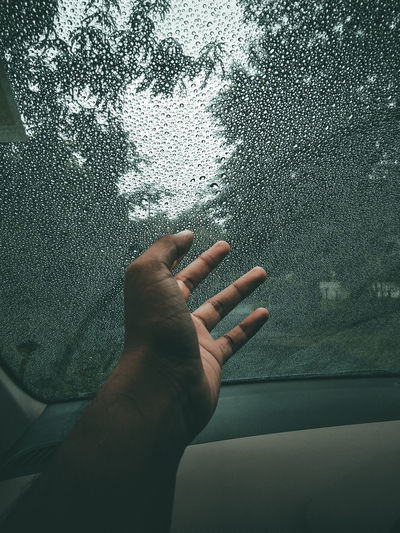 Person hand on wet glass of car