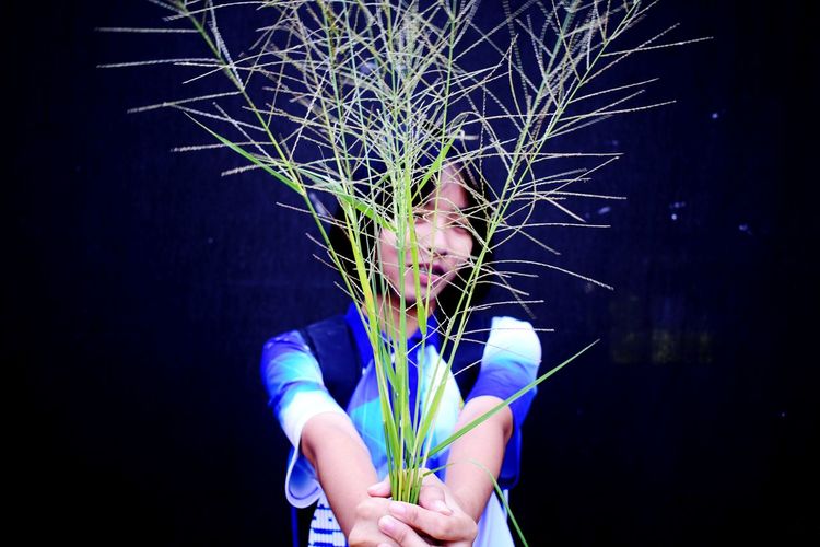Full length of young woman holding illuminated plant