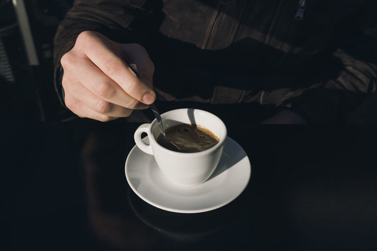 Midsection of man holding coffee on table