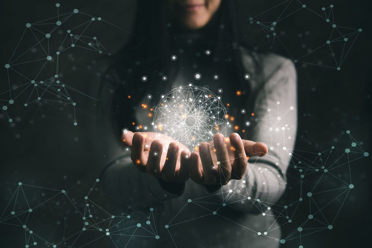 Digital composite image of hand holding illuminated sparkler against black background