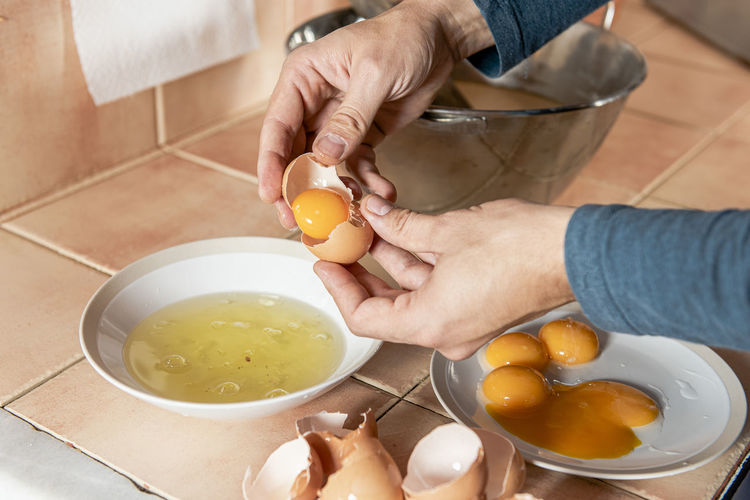 Middle aged man separating and mixing eggs to cook homemade pastry