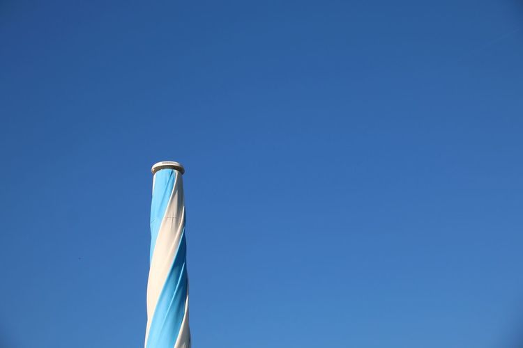 Low angle view closed parasol  against clear blue sky