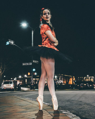 Full length of ballet dancer dancing on street at night
