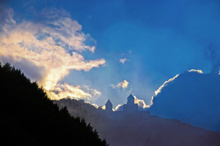 Low angle view of silhouette mountain against blue sky