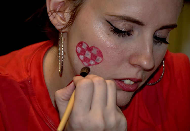 Close-up of woman making heart shape on cheek