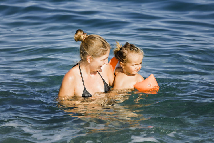 Mother swimming with daughter in sea