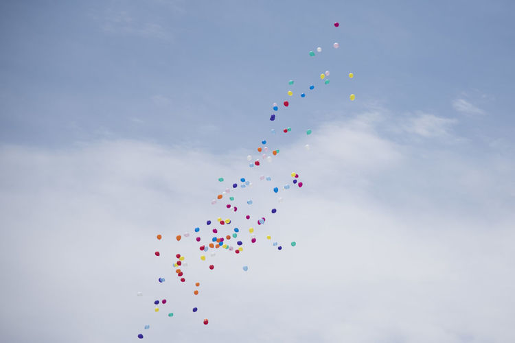 Low angle view of multi colored balloons flying in sky