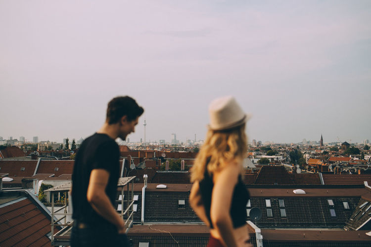 Friends walking on terrace by cityscape against sky