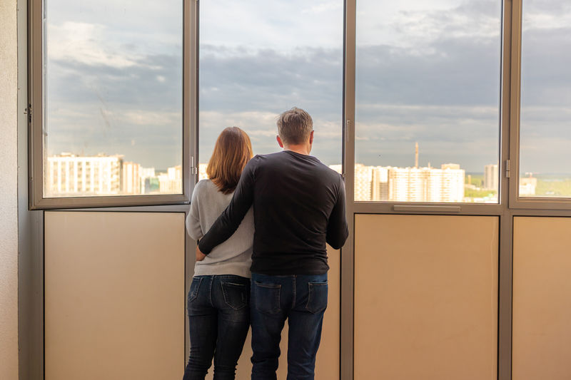 Man hugging his wife. young couple moving in new apartmen. people looks out window at new houses. 