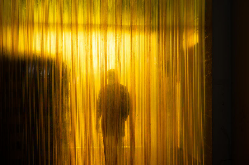 Yellow industrial plastic curtain entrance with shadow of worker and cardboard box in warehouse