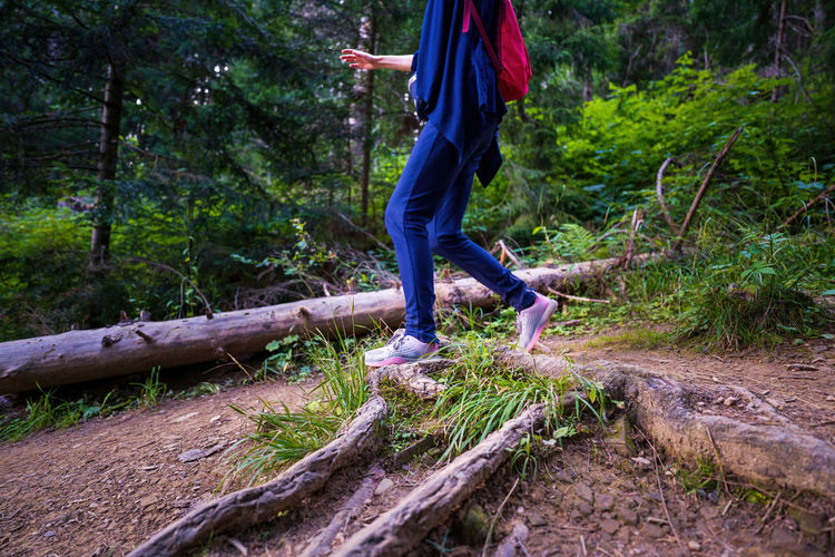 Woman hiker legs wearing sports shoes hiking in woods or forest with backpack adventure lifestyle