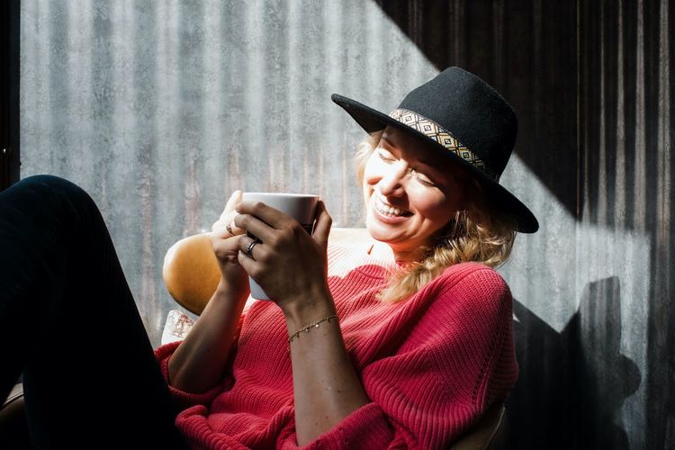 Portrait of a woman drinking coffee in a cafe smiling in the sunshine