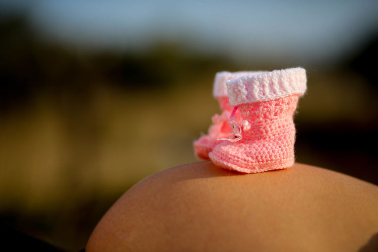 Close-up of pregnant woman with baby booties on abdomen