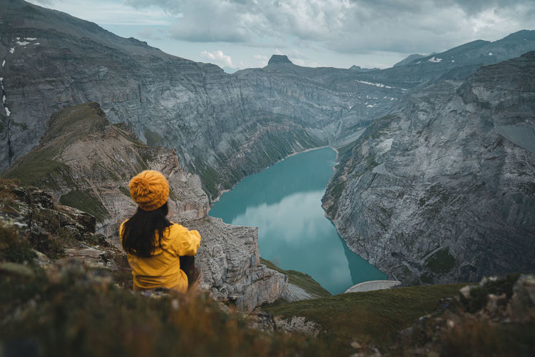 Young woman in yellow jacket looking at view in glarus, limmernsee lake