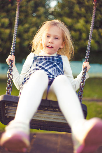 Low angle view of girl sitting on swing at park