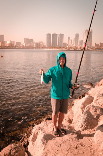Full length portrait of man standing in sea against sky