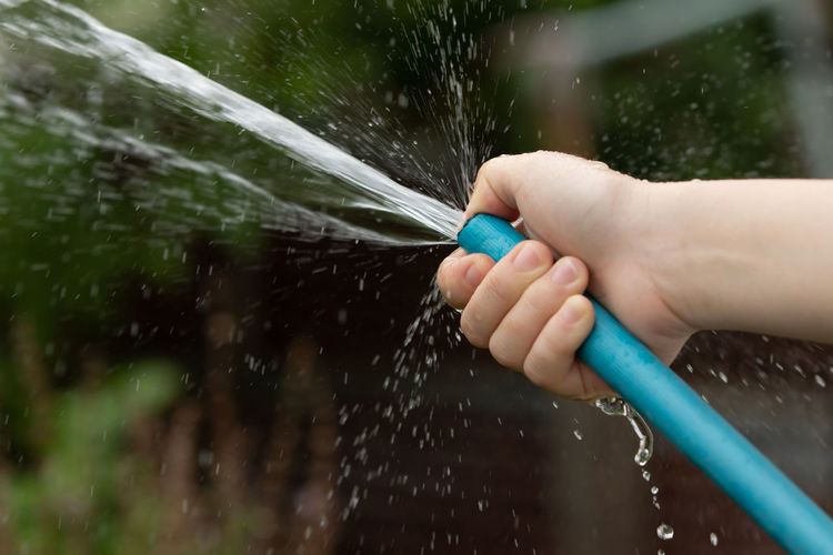 Cropped hand of person holding water hose