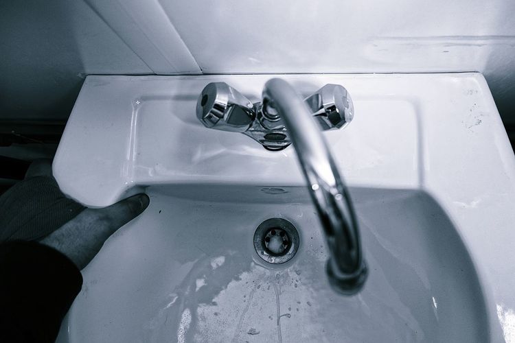 High angle view of person hand on wash bowl in bathroom