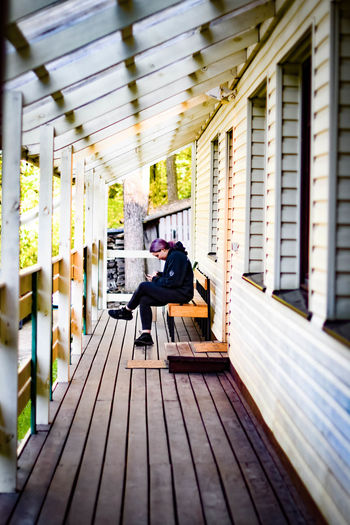 Side view of woman sitting on bench against building