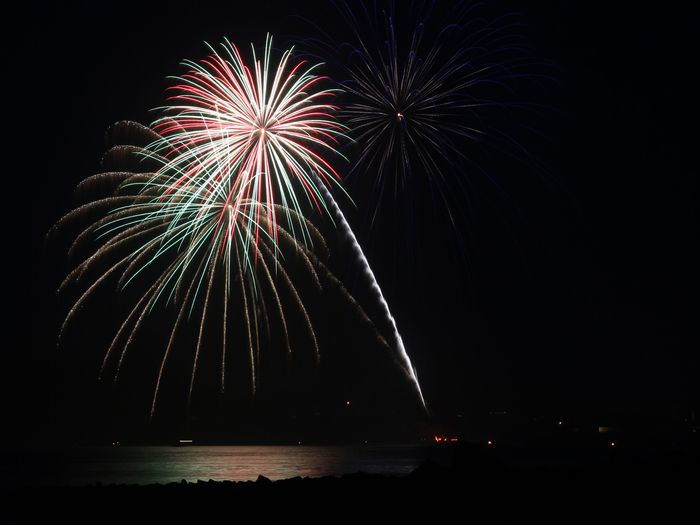 Illuminated fireworks over lake against sky at night
