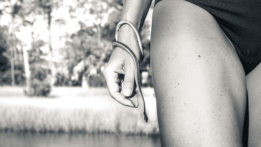 Midsection of woman in swimwear holding snake