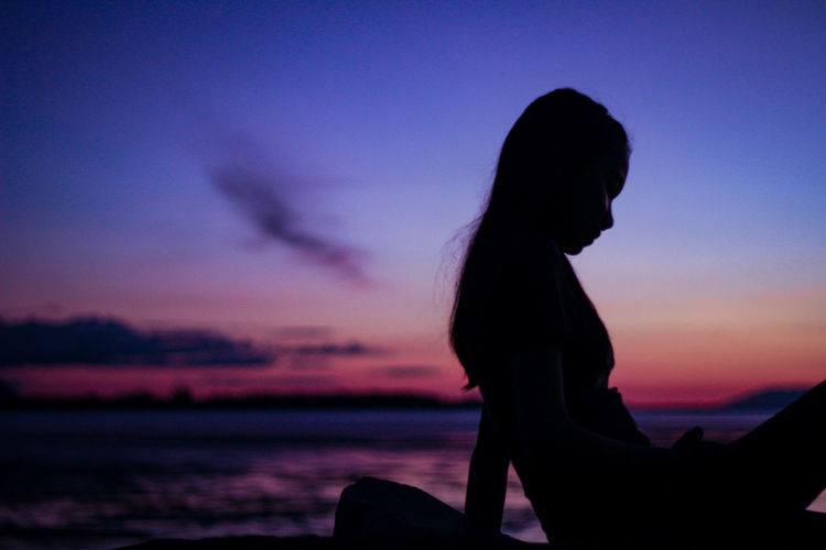 Silhouette girl at beach against sky during sunset