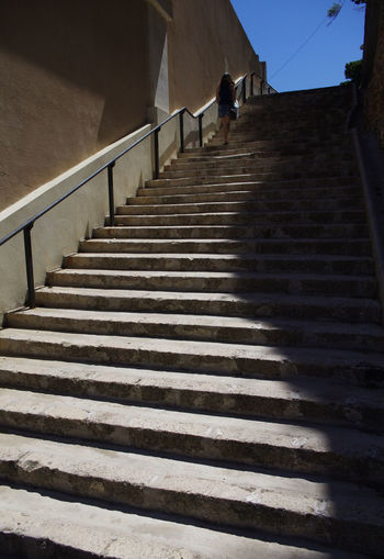 Rear view of woman walking on steps against sky