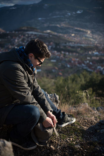 Full length of man sitting on cliff