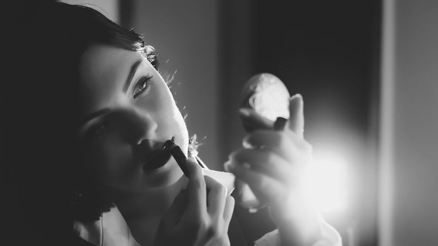Close-up of young woman applying lipstick