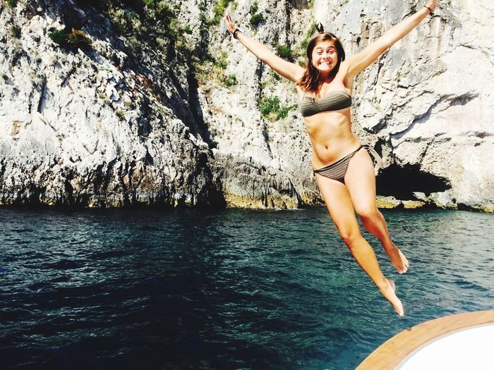 Young woman wearing bikini while jumping in sea