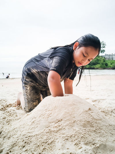 Cute girl making sandcastle on beach