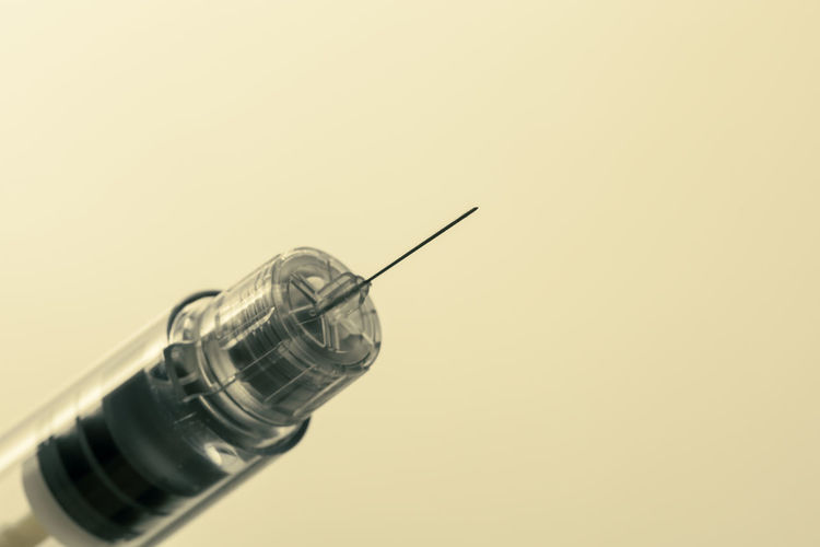 Close-up of syringe against pink background