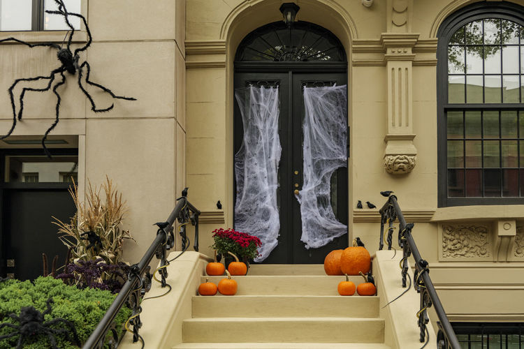 Assorted halloween decorations guard the front steps of a house. pumpkins on a porch.